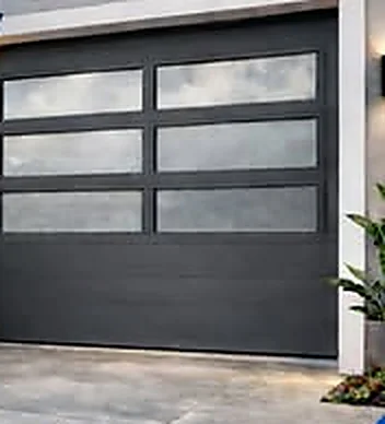 Puerta de garaje en aluminio moderna, color gris oscuro, con tres hileras de paneles de vidrio esmerilado en la parte superior